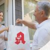 Frau nimmt an der Haustür Lieferung der Apotheke entgegen.